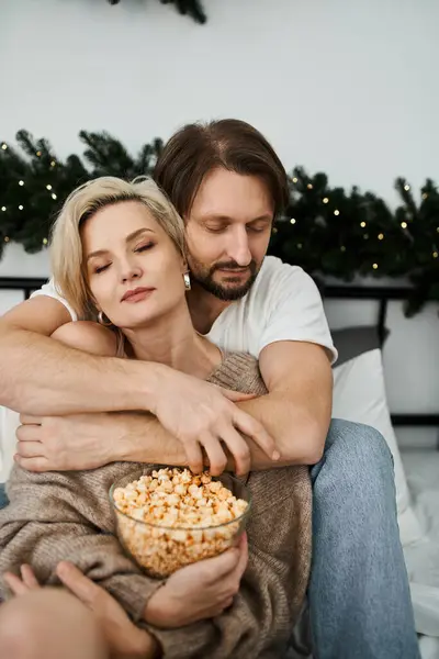 A couple cuddles on the couch, sharing popcorn and enjoying each others warmth. — Stock Photo