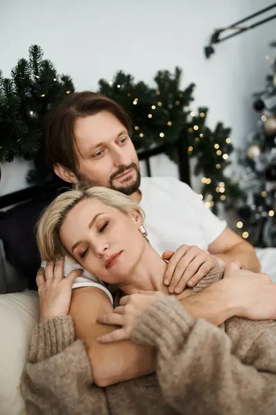 A couple embraces tenderly on a cozy couch, surrounded by festive decorations and joy. — Stock Photo