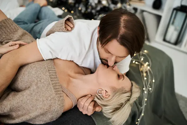 A couple shares warm kisses on a cozy couch surrounded by festive decor. — Stock Photo