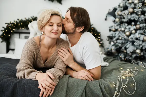 Un couple amoureux profite d'une douce étreinte sur un lit de fête avec des décorations de vacances à proximité. — Photo de stock