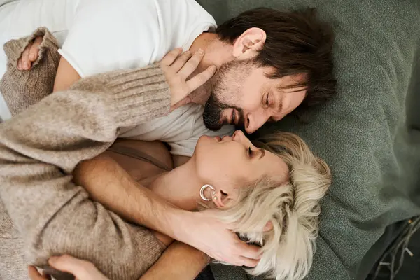 A couple enjoys a tender embrace while lying on a soft couch, sharing warmth and affection. — Stock Photo