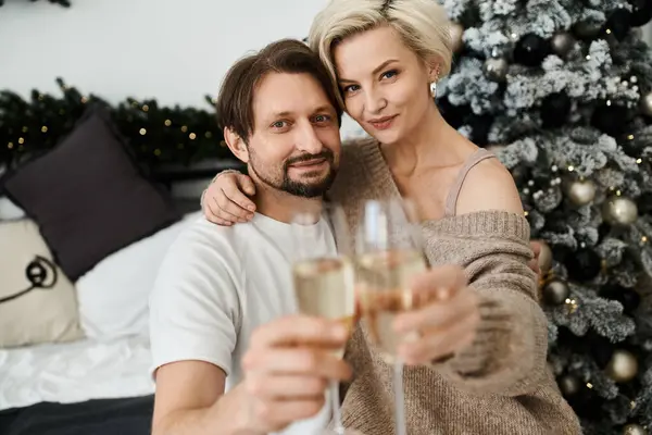 A joyful couple holds glasses of champagne, sharing a moment of love and warmth at home. — Stock Photo