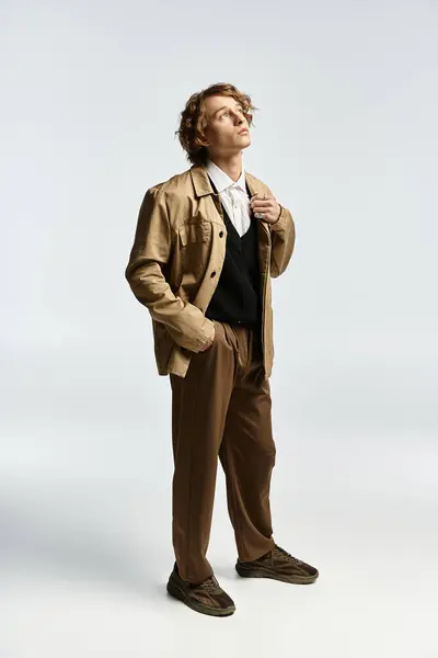 A handsome young man stands confidently in a chic autumn ensemble, exuding elegance in a studio. — Stock Photo