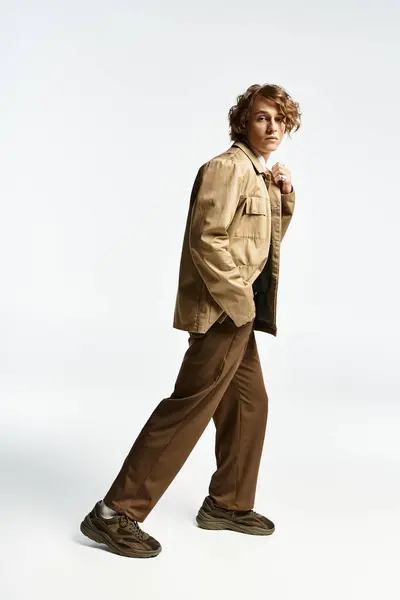 A striking young man displays his wavy hair and elegant autumn outfit in a contemporary studio. — Fotografia de Stock