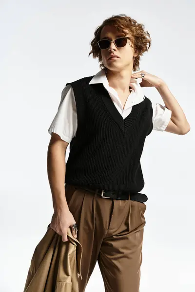 A handsome young man in a chic autumn outfit poses elegantly, highlighting his trendy style and wavy hair. — Stock Photo