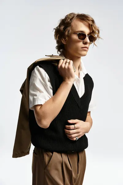 A handsome young man showcases his wavy hair and chic autumn outfit while striking a pose in the studio. — Stock Photo