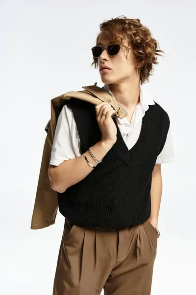 A handsome young man with wavy hair exhibits autumn-inspired fashion in a chic studio space. — Stock Photo