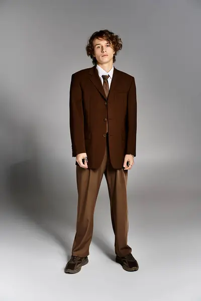 Dressed in a brown suit a young man stands confidently in a sleek studio environment. — Stock Photo