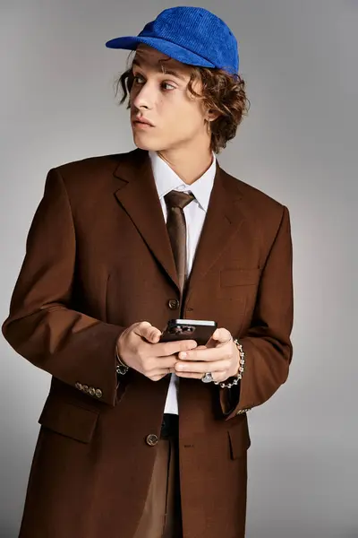 A stylish young man dressed in a brown suit checks his phone while looking curated in a studio environment. — Stock Photo