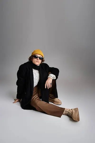 With a casual yet fashionable look, a young man showcases his style in a studio wearing a yellow beanie. — Stock Photo
