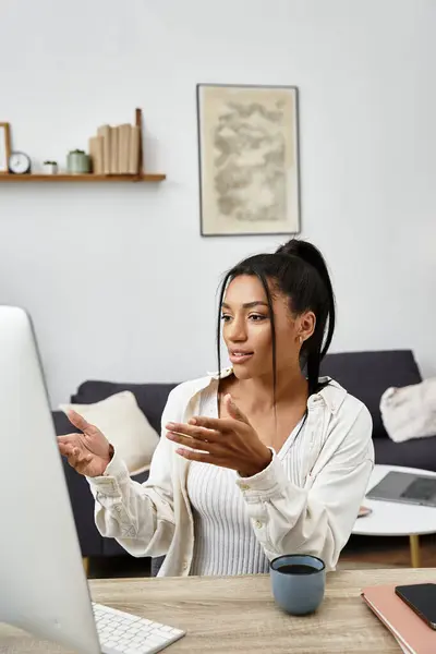 Eine junge Frau lernt aktiv von zu Hause aus, beschäftigt sich mit ihrem Computer und genießt ein warmes Getränk. — Stockfoto