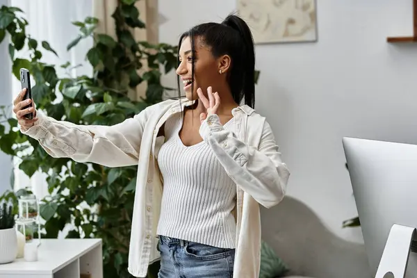 Luminosa e allegra, una giovane donna studia a distanza, connettersi con gli altri attraverso il suo telefono. — Stock Photo