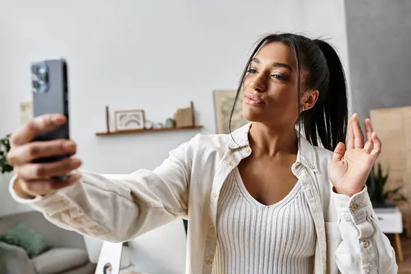 The young woman smiles and waves as she studies remotely, creating a cheerful atmosphere. — Stock Photo