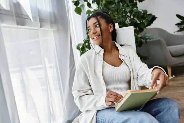 A dedicated student learns from home, soaking in the sunlight through large windows. — Stock Photo