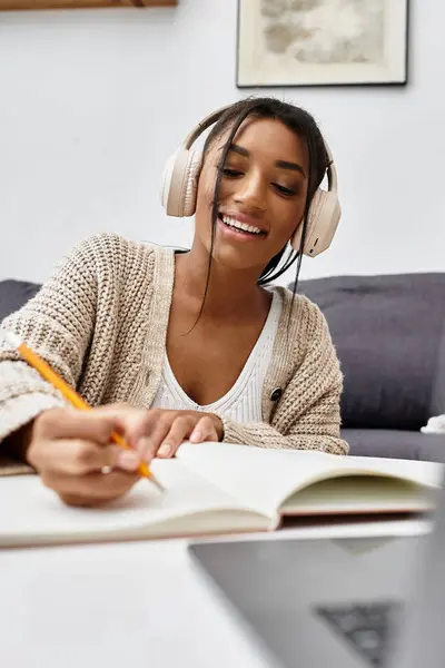 A cheerful young woman is deeply engaged in her studies at home, taking notes with a pencil. — Stock Photo