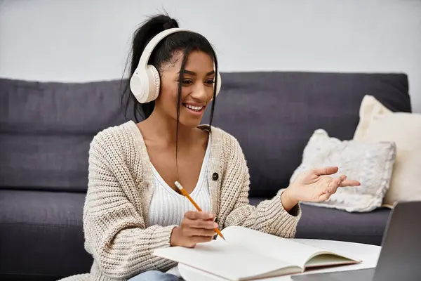 In a cozy living room, a young woman joyfully participates in an online study session. — Stock Photo