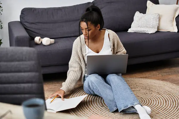 The young woman is deeply focused on her studies while sitting on the floor at home. — Stock Photo