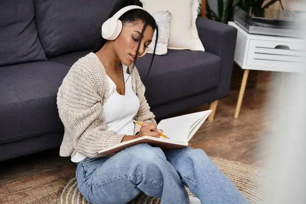 The young woman sits on the floor, dedicated to studying while immersed in a notebook. — Stock Photo