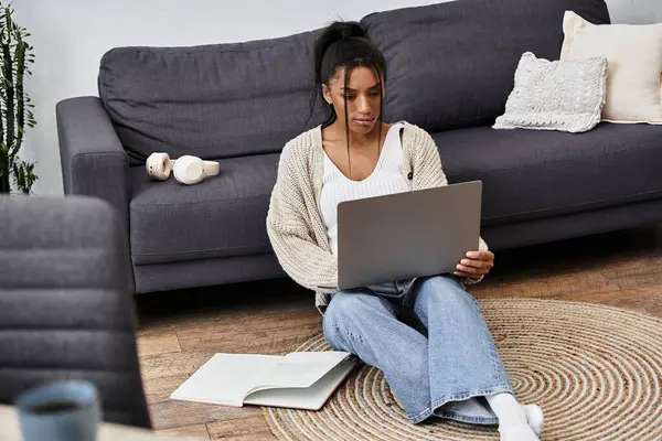 The young woman is engaged in her studies on a laptop, seated on a soft rug at home. — Stock Photo