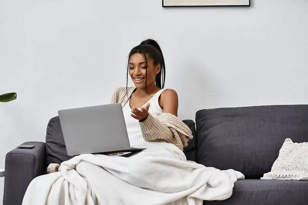 A young beautiful woman joyfully participates in online learning while relaxing on her couch. — Stock Photo