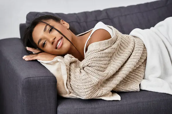 The young woman relaxes on her couch, studying comfortably while enjoying her surroundings. — Fotografia de Stock