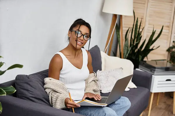 A young woman happily studies from her home, surrounded by greenery and comfort. — Stock Photo