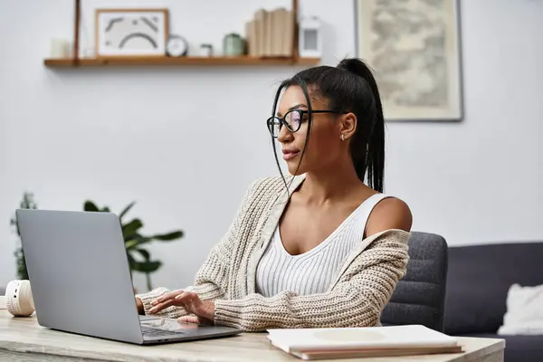 A beautiful young woman is engaged in remote learning, tapping away on her laptop at home. — Stock Photo