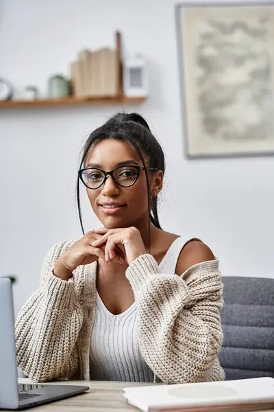 A beautiful young woman studies intently at her home desk, surrounded by a comfortable atmosphere. — Stock Photo