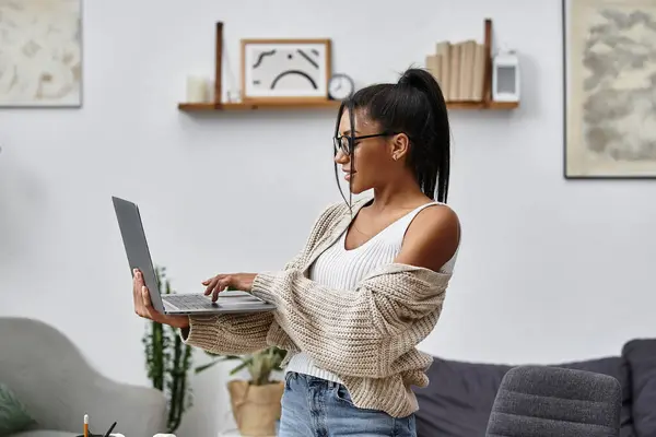 Die Frau greift zu ihrem Laptop und genießt eine produktive Arbeitssitzung in ihrem stilvollen Zuhause. — Stockfoto