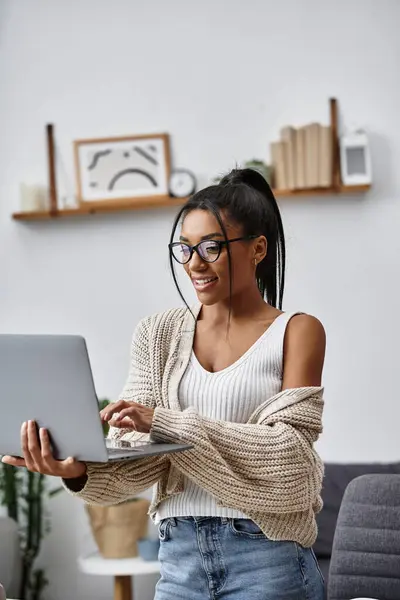 A cheerful woman engages in remote study while seated comfortably at home, feeling inspired. — Stock Photo