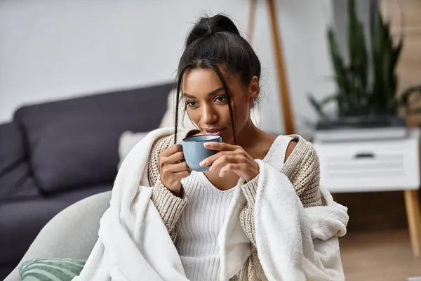 She sips her drink and immerses herself in studies, wrapped in a warm blanket on a chilly day. — Stock Photo