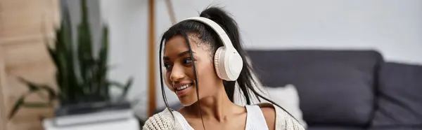 A young woman engages in remote study while comfortably seated at home, focused and happy. — Stock Photo