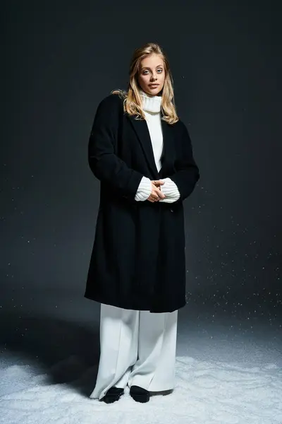 Dressed in elegant winter attire, a young woman poses confidently amidst a soft snowy backdrop. — Stock Photo
