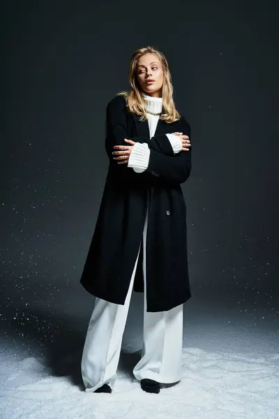 Una mujer joven con estilo se para con confianza, vestida para el invierno con un abrigo elegante y un suéter acogedor. - foto de stock