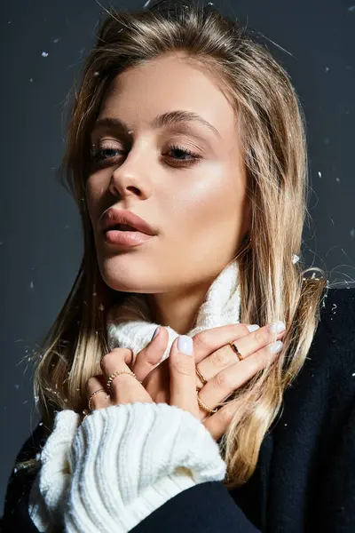 A young woman gazes thoughtfully while wearing cozy winter clothing, surrounded by soft snowflakes. — Stock Photo