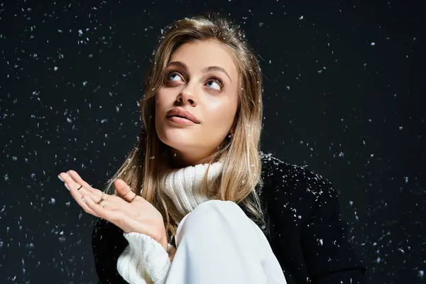 A young woman playfully catches snowflakes, showcasing her joy and fashion amid a winter backdrop. — Stockfoto