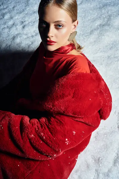 A beautiful young woman looks confident in a vibrant red outfit against a snowy setting. — Stock Photo