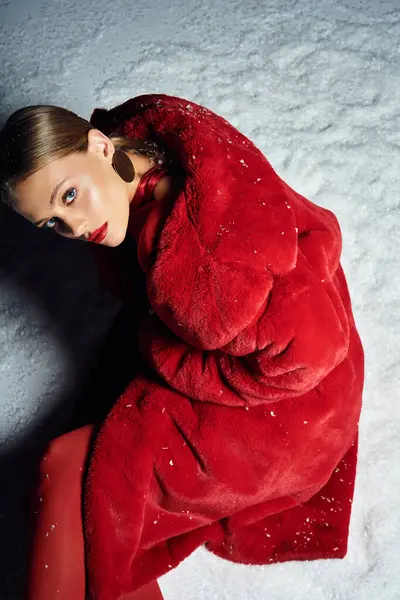 Eine stylische junge Frau in auffallend rotem Mantel posiert elegant inmitten einer heiteren, verschneiten Kulisse. — Stockfoto