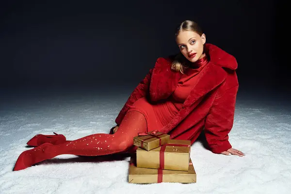 A young woman in festive red is surrounded by gifts, radiating holiday cheer. — Stock Photo