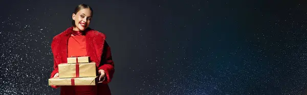 A stylish young woman enjoys the holiday spirit with wrapped gifts and falling snow. — Stock Photo