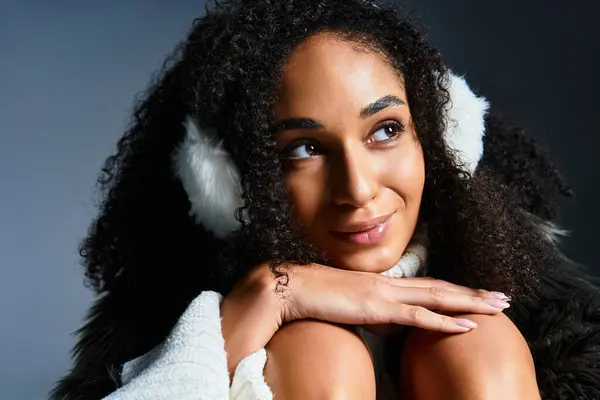 Una donna bruna elegante mette in mostra la moda invernale in paraorecchie e una giacca di pelliccia ecologica chic mentre posa calorosamente. — Foto stock