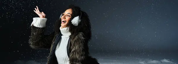 Una donna bruna gioiosa mette in mostra il suo stile invernale, indossando paraorecchie e una giacca di pelliccia ecologica mentre si gode il momento. — Foto stock