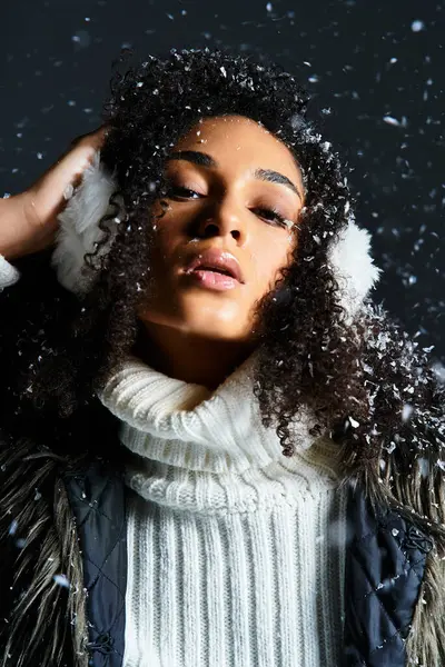 A beautiful brunette woman showcases winter style with earmuffs and a cozy faux fur jacket in a studio. — Stock Photo