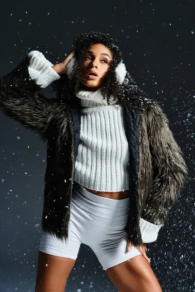 Una bella donna afroamericana mette in mostra accogliente moda invernale, indossando paraorecchie e una giacca di pelliccia sintetica. — Foto stock
