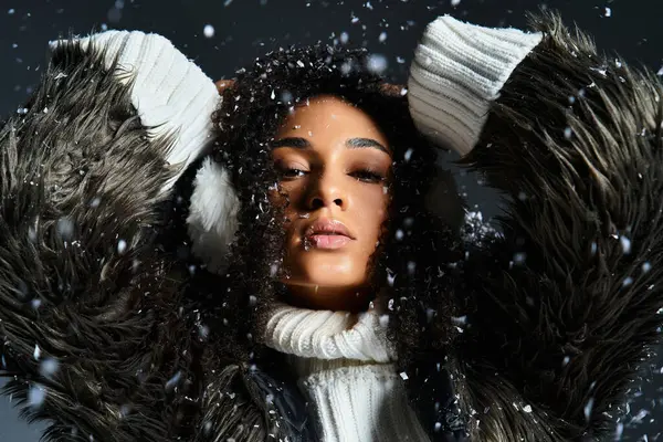 A beautiful African American woman models winter fashion, donning earmuffs and a cozy faux fur jacket. — Stock Photo