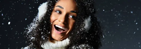 Una donna bruna gioiosa mette in mostra il suo stile invernale, indossando paraorecchie e un'accogliente giacca di eco-pelliccia, in uno studio. — Foto stock