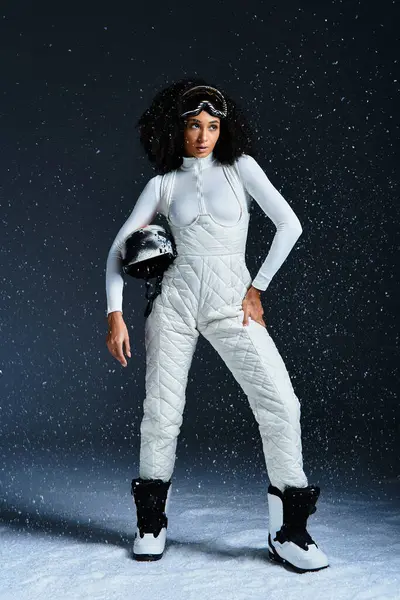 A beautiful African American woman models a chic ski suit, embodying winter fashion in a studio space. — Stock Photo