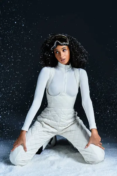 A beautiful brunette woman in a ski suit poses elegantly against a snowy backdrop, highlighting winter fashion. — Stock Photo