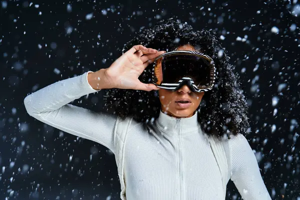 Uma mulher morena confiante exibe moda de inverno elegante com flocos de neve caindo suavemente ao redor dela. — Fotografia de Stock
