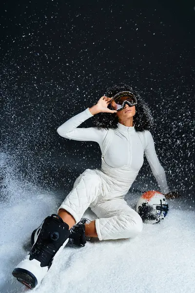 Una mujer morena de moda posa con confianza en un traje de esquí, encarnando el estilo invernal mientras disfruta del momento. - foto de stock